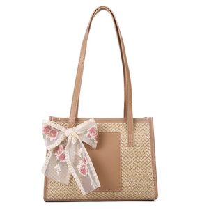 Women's straw tote bucket bag with white lace bow and adjustable leather shoulder strap