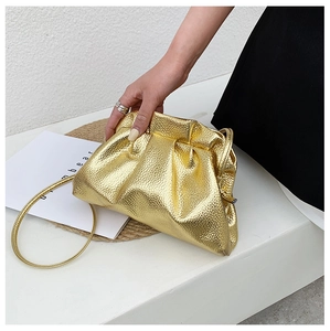 Detail showing metallic gold gathered cloud bag with fine pebble texture and slim strap