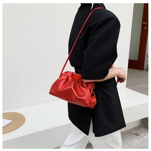 Detail of red dumpling bag with metallic texture worn as a stylish underarm bag