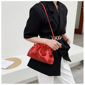 Red metallic cloud bag worn by a model with a cross-body strap and pleated detail