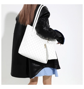 Detail of white quilted tote bag with matching mini pouch and gold zipper on a model