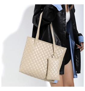 Detail view of beige quilted tote bag with matching zippered pouch and shoulder strap