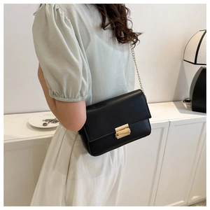 Detail of black faux leather bag featuring a gold metal buckle and elegant chain strap
