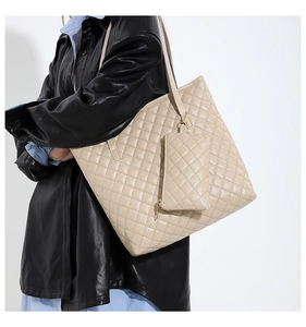 Close-up of quilted beige tote bag with detachable mini pouch on a leather jacket model