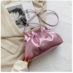 Detail of metallic pink cloud bag with soft pleats and textured leather on a beige coat