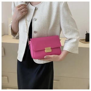 Detail of fuchsia leather crossbody bag with golden chain strap and buckle closure