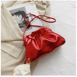 Detail of red metallic pleated cloud bag with textured synthetic leather on beige fabric
