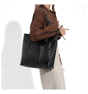 Side view of black quilted tote bag and matching mini pouch on a model with natural lighting