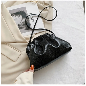 Close-up of black cloud bag with lychee grain texture and minimalist leather strap