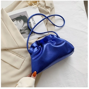 Detail of blue metallic cloud bucket bag with pleated texture and adjustable strap
