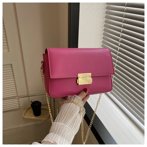 Detailed view of the vibrant rose red leather texture and gold chain strap of the bag