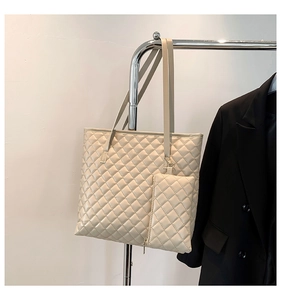 Detail of beige quilted tote bag with matching pouch on hanger next to a black blazer