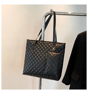 Detail shot of black quilted tote bag texture with matching mini pouch on stainless hanger