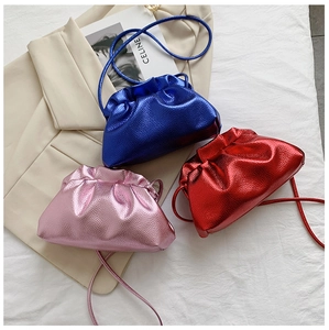 Close-up of metallic leather bucket bags with drawstring pleats in blue, red, and pink