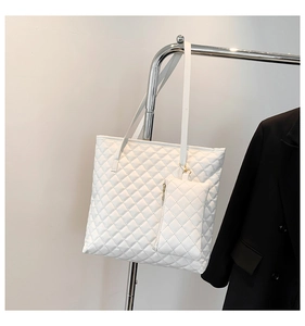Close-up of white quilted tote bag set with matching small pouch on a metal display stand