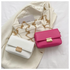 Chic chain strap shoulder bags in white and pink displayed on a beige blazer