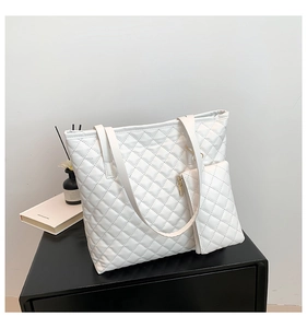 Close-up of white quilted tote bag and matching pouch with elegant diamond pattern