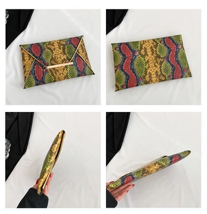 Macro detail of snakeskin pattern envelope clutch bag with colorful patchwork and gold bar