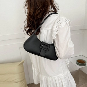 Minimalist black matte leather shoulder bag with buckle shown on model with white dress