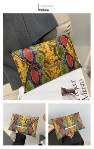 Detail of yellow snakeskin envelope clutch bag with vibrant color print and gold metal trim