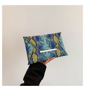 Detail of blue and yellow snakeskin envelope clutch with elegant gold V-shape metal trim