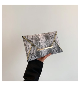 Detail of grey snakeskin clutch bag featuring golden metal trim and sleek envelope design