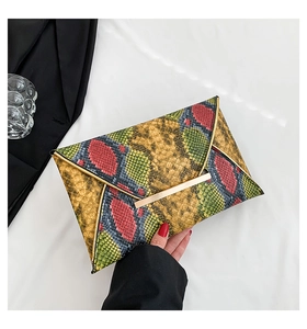Detail of colorful snakeskin envelope clutch bag with gold bar closure and reptile texture