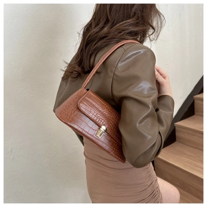 Brown crocodile pattern baguette bag worn on shoulder with golden metal buckle clasp