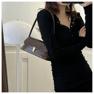 Detail of dark brown faux crocodile leather shoulder bag with golden metallic buckle