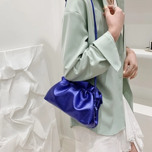 Chic electric blue dumpling bag with drawstring and thin strap on a stylish model