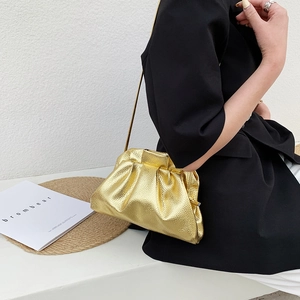 Metallic gold pleated cloud bag with thin chain strap worn by model on shoulder