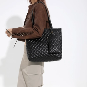 Classic black quilted tote bag with matching pouch shown on model for autumn fashion