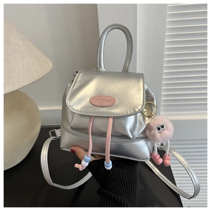 Close-up of metallic silver mini backpack with pink plush monster charm and bead detail
