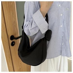 Detail of black nylon crescent bag with mini pouch on blue striped shirt