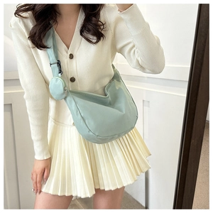 Light green half-moon crossbody bag with matching round coin purse detail on a model