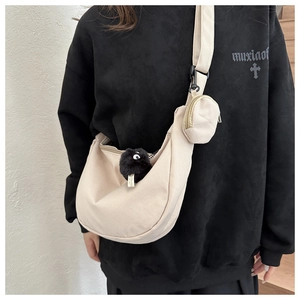 Detail of beige corduroy crescent crossbody bag with mini pouch and coal sprite charm