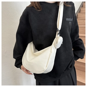 Detail view of cream canvas crescent bag featuring a detachable small round coin purse