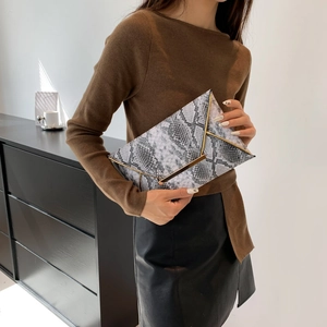 Chic snake print envelope clutch bag with gold metallic frame held by a model