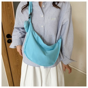 Detail view of light blue crescent crossbody bag with small round coin pouch on strap
