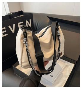 Detail of beige canvas tote bag featuring black woven rope knot and leather logo tag