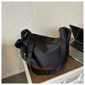 Detail of black canvas tote bag with small pouch and plush ball on wooden table