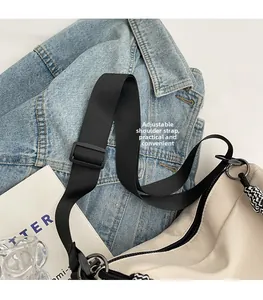 Close-up of the adjustable black shoulder strap buckle on a cream canvas tote bag