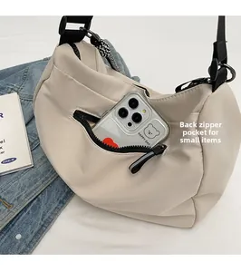 Detail of the back zipper pocket on a beige crescent tote bag with a smartphone inside