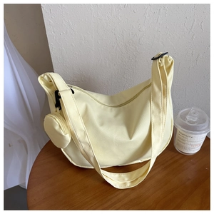 Detail of light yellow half-moon canvas crossbody bag with small round coin purse