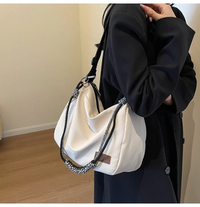 Detail showing the cream canvas tote bag with braided rope strap and leather logo tag