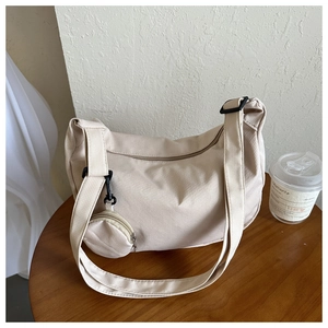 Macro detail of beige nylon crossbody bag texture with wide strap and round coin purse