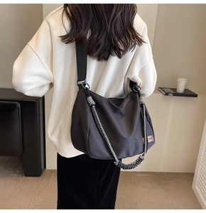 Detail of large dark grey nylon hobo bag with contrast woven rope and leather logo patch