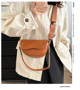 Détail du sac selle marron caramel avec large bandoulière tissée et chaîne dorée