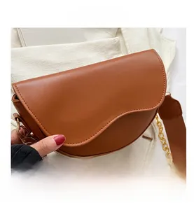 Détails latéraux du sac selle marron avec chaîne dorée et bandoulière tissée