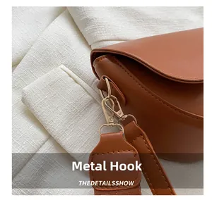 Détail du crochet métallique doré sur un sac en cuir marron avec large bandoulière
